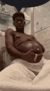 a shirtless man is holding his pregnant belly
