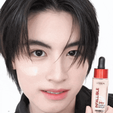a young man holds a bottle of l' oreal infallible 24h tinted serum
