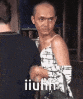a bald man in a dress is shaking hands with another man while holding a purse .