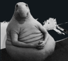 a black and white photo of a stuffed animal sitting on a couch