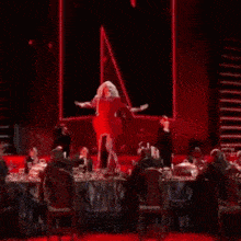 a woman in a red dress is dancing on a stage with a microphone .