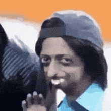 a man wearing a hat and a blue shirt is making a funny face