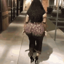 a woman is walking down a sidewalk wearing heels and a snake print skirt