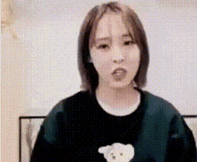 a woman is wearing a black sweater with a teddy bear on it and making a funny face .
