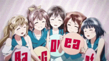 a group of anime girls are posing for a picture while holding signs with the letters a and g .