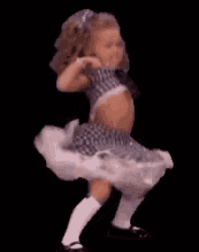 a little girl is dancing on a black background .