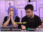 a woman with blue hair wipes her nose while a man asks her if she is ok