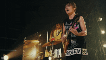 a man playing a guitar in front of a large screen that says ' nirvana ' on it