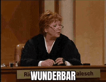 a woman sitting at a desk with a sign that says wunderbar