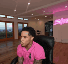 a man in a pink polo shirt sits in a chair in front of a sign that says safe