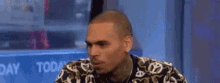 a man in a camouflage jacket is sitting in front of a television .