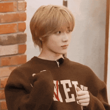 a person wearing a brown sweater that says new