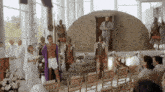 a man in a robe stands in front of a group of people dressed in roman costumes