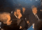 a group of men are sitting in a dark room .