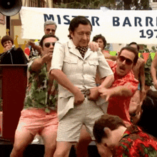 a group of men are dancing in front of a sign that says mister barro