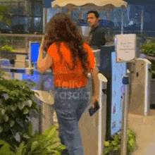 a woman in an orange shirt is standing in front of a kiosk that says telly masala