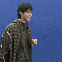 a young man wearing a plaid shirt and a necklace is smiling and holding a sign that says " winner nicholas "