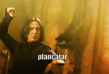 a man in a black shirt is holding a wand and the word plancatar is on the bottom