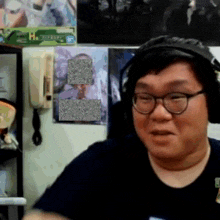 a man wearing glasses and headphones stands in front of a wall with a picture of a man on it
