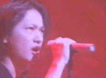 a woman is singing into a red microphone on a stage .