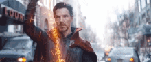 doctor strange is standing in the middle of a city holding a sword in his hand .