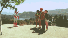 a group of people standing on top of a hill watching a superhero