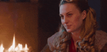 a woman is sitting in front of a fireplace with a candle in her hand .