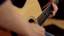 a close up of a person playing an acoustic guitar with a ring on their finger