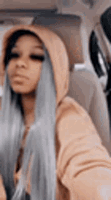 a woman in a hoodie is sitting in the back seat of a car taking a selfie .