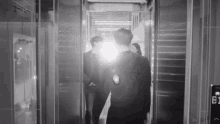 a group of people are walking out of an elevator with a light shining on them .