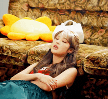 a woman laying on a couch with her eyes closed next to a stuffed sunflower