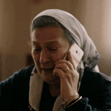 a woman wearing a head scarf is talking on a phone