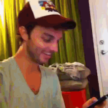 a man wearing a hat with the word ed hardy on it looks at his phone