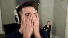 a young man wearing headphones covers his face with his hands