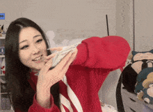 a woman in a red sweater is holding a bunch of money in her hand