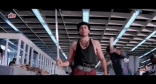 a man in a black tank top is holding a sword in a room with a sign that says ultra on it