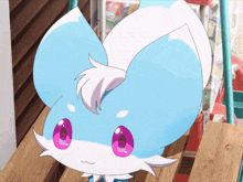 a blue and white animal with pink eyes is sitting on a wooden shelf