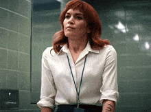 a woman with red hair is wearing a white shirt and a lanyard