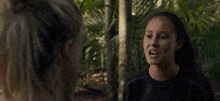a woman is touching another woman 's face in the jungle .