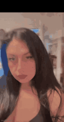 a young woman with long black hair is wearing a black bra and looking at the camera .