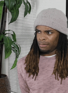 a man with long dreadlocks wearing a beanie and a pink shirt