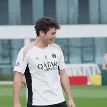 a man wearing a white qatar airways shirt smiles