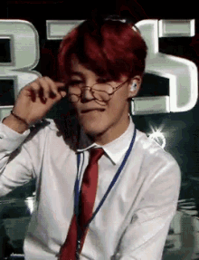 a man with red hair is wearing glasses and a red tie .
