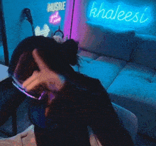 a person pointing in front of a neon sign that says khaleesi