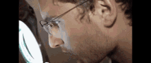 a close up of a man wearing glasses looking through a magnifying glass