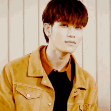 a young man wearing a brown jacket and a black shirt