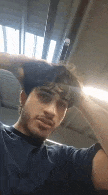 a man with a beard is holding his hand to his head in a gym .