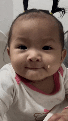 a baby girl with pigtails on her head is making a face