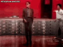 a man in a suit and sunglasses is dancing on a dance floor