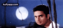 a man is standing in front of a full moon in a dark room .